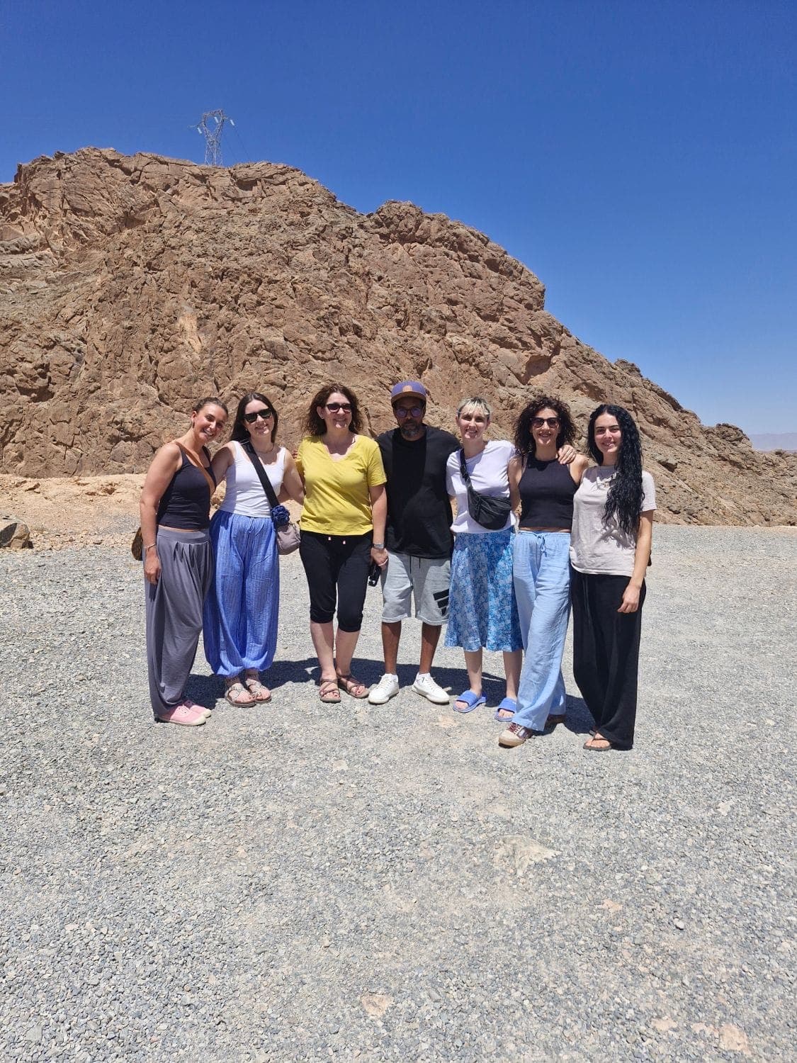 A group of travellers posing by a rocky mountain under a deep blue sky
