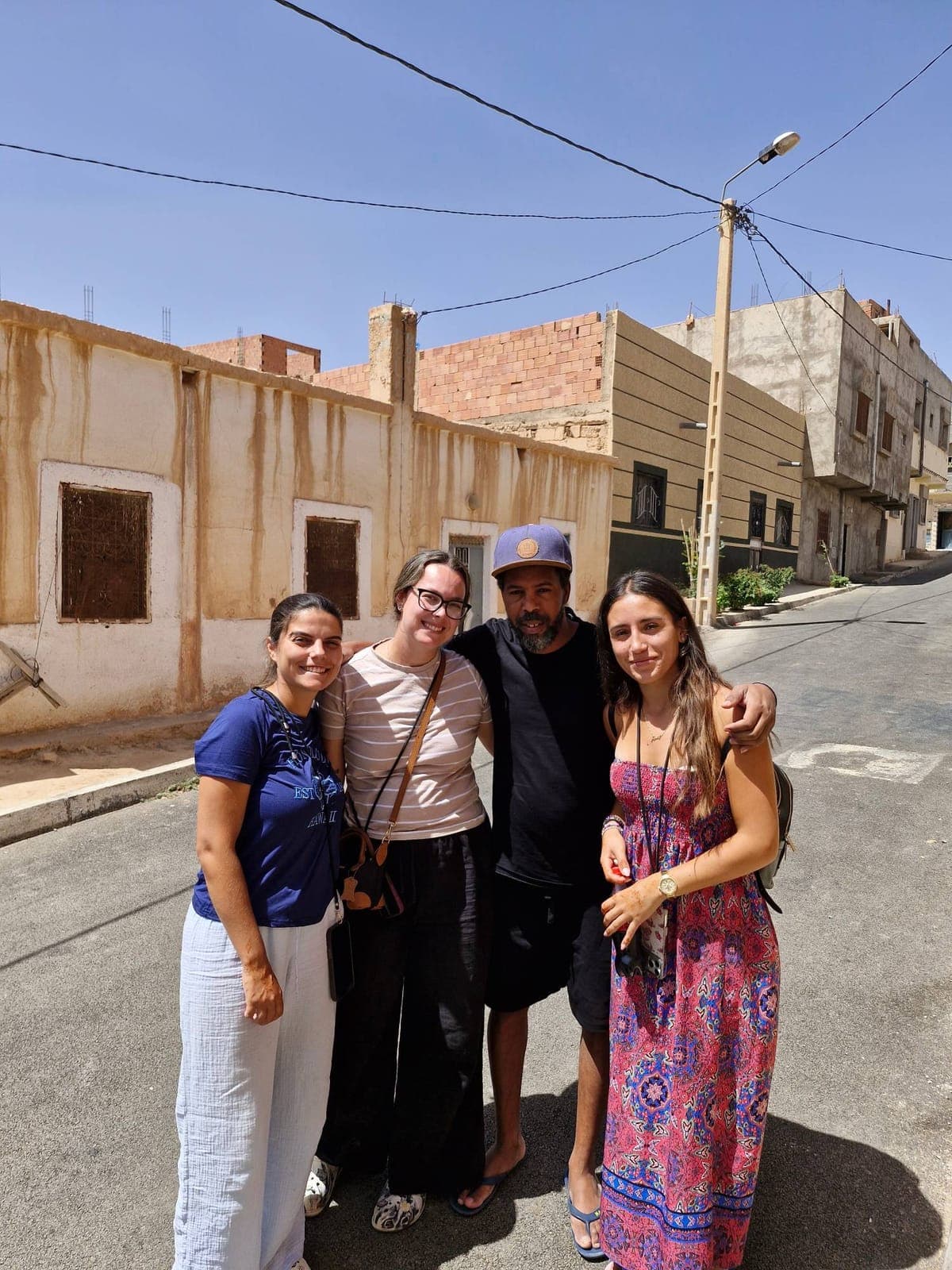Four smiling travellers posing together in a street of a Moroccan town