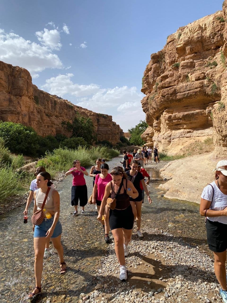 Grupo de senderistas caminando por el cauce de un río entre paredes de roca